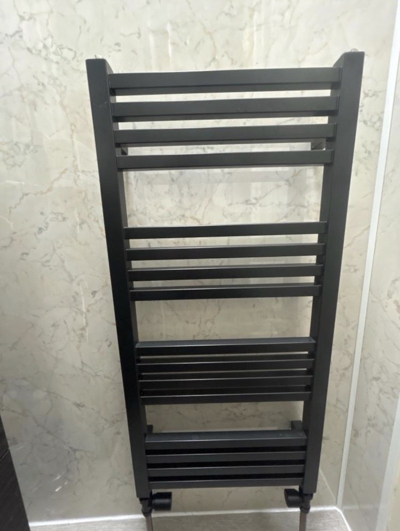 Black heated towel rail fitted in a bathroom