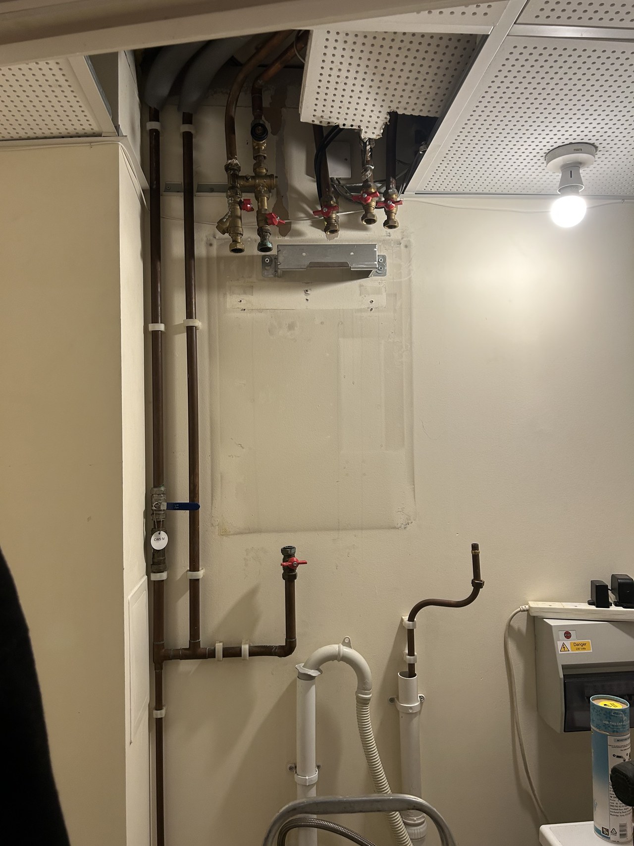 Flow and return pipework, valves and a heat meter in a cupboard